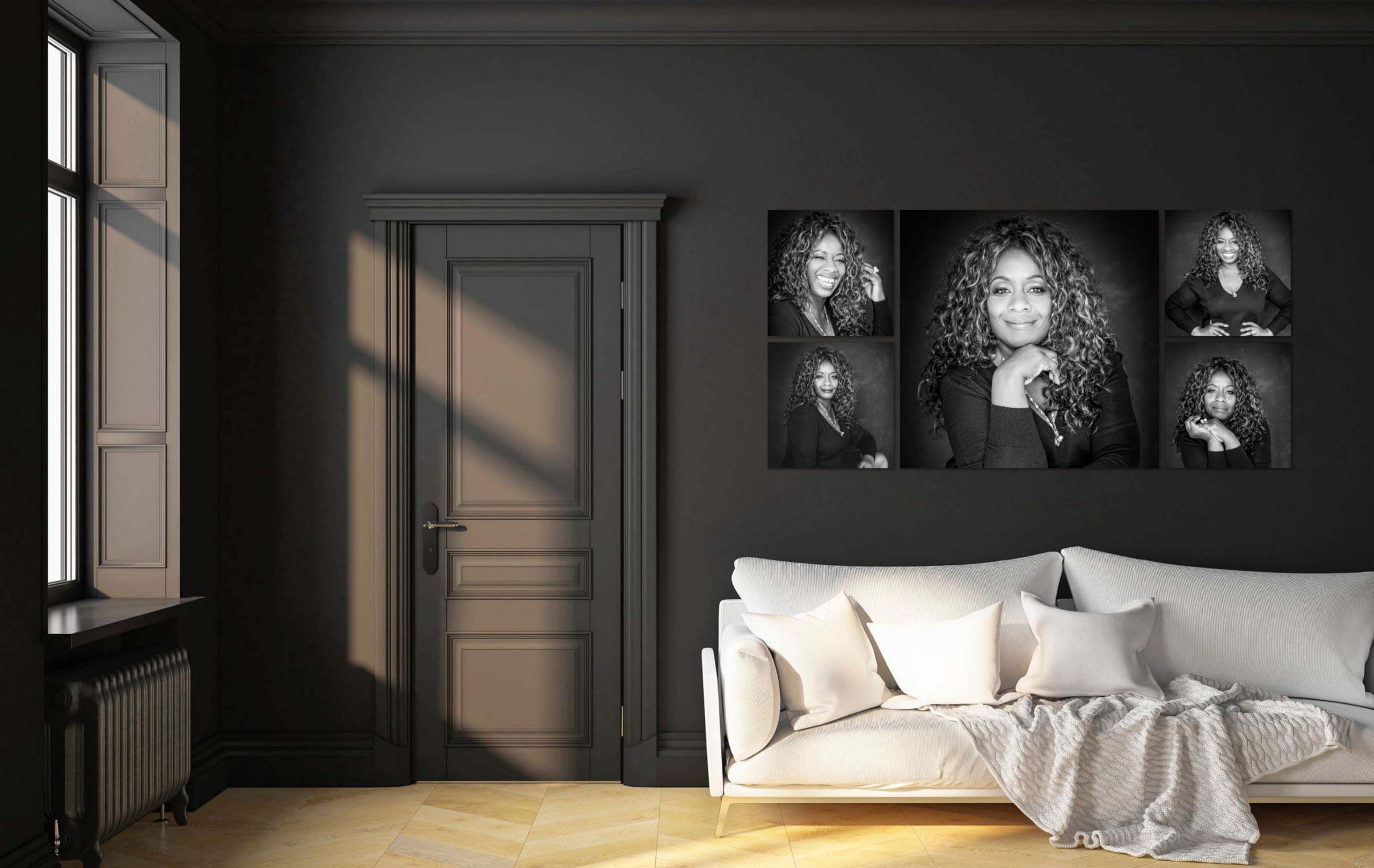 Modern living room with dark walls, a closed gray door, and a white sofa with several white pillows and a textured throw blanket. Above the sofa is a collage of five black-and-white portraits of a woman with curly hair, smiling and posing in different expressions.
